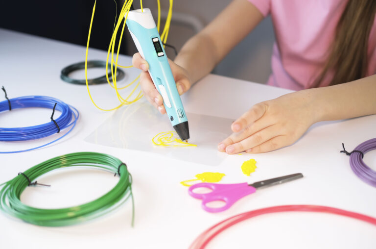 3D printable pen, hands holding colorful toy. Colored plastic in rolls. STEM education. Play and learn at school and at home. New toy for child.
